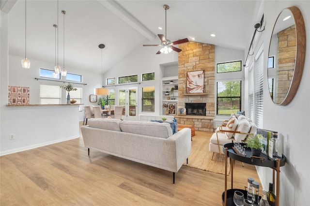 living room featuring ceiling fan with notable chandelier, a fireplace, plenty of natural light, and light hardwood / wood-style floors