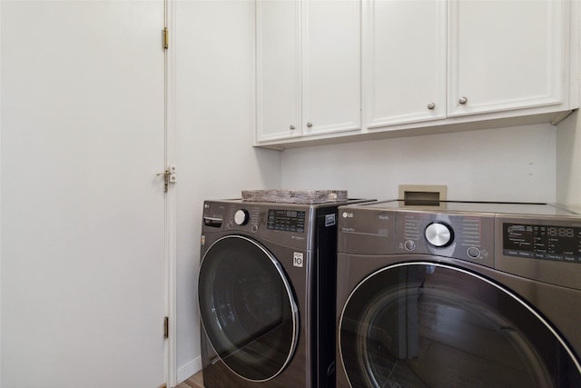 washroom with washing machine and clothes dryer and cabinets