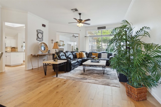 living room featuring light wood-type flooring, ceiling fan, and ornamental molding