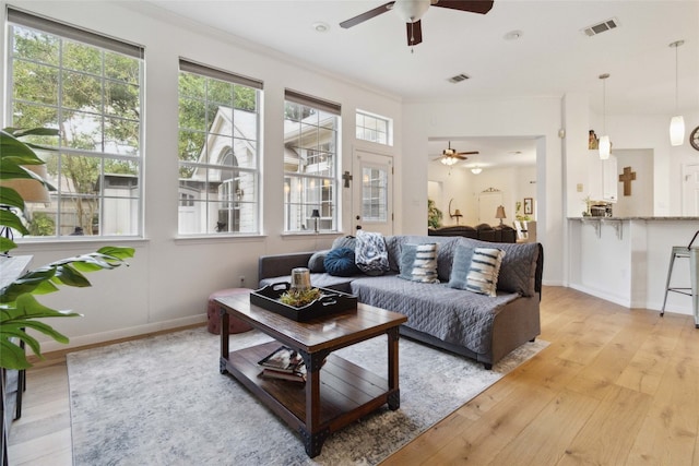 living room with ceiling fan, ornamental molding, and light hardwood / wood-style floors