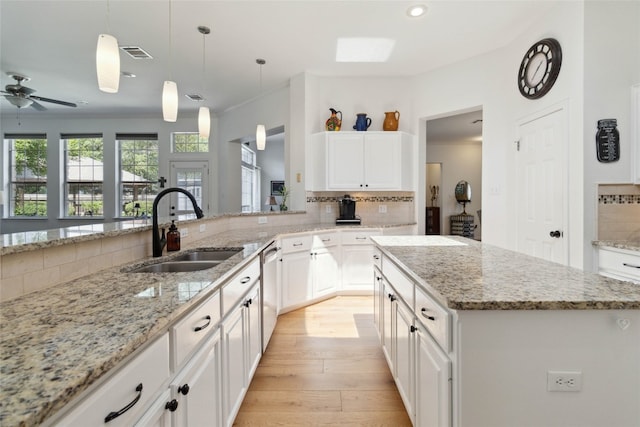 kitchen with a kitchen island, sink, decorative light fixtures, and light hardwood / wood-style floors