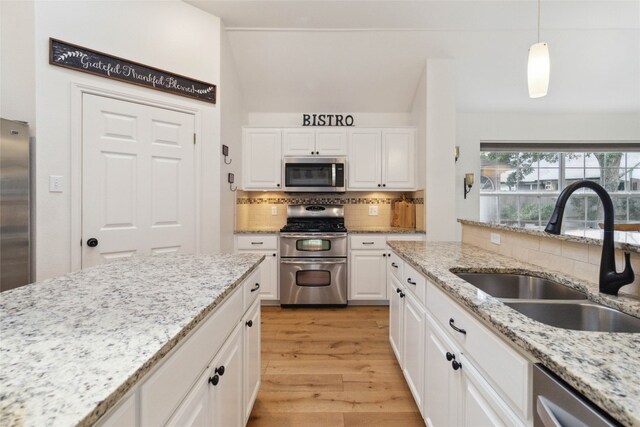 kitchen with light hardwood / wood-style flooring, backsplash, appliances with stainless steel finishes, sink, and light stone counters