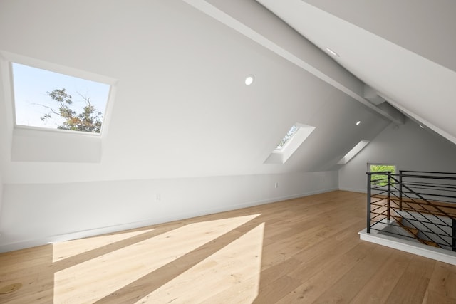 additional living space featuring light hardwood / wood-style flooring and lofted ceiling with skylight