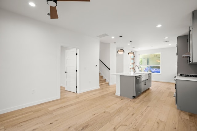 kitchen featuring light hardwood / wood-style flooring, ceiling fan, gray cabinets, pendant lighting, and a center island with sink