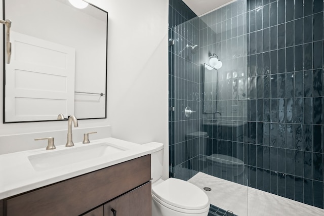 bathroom with toilet, a tile shower, and vanity