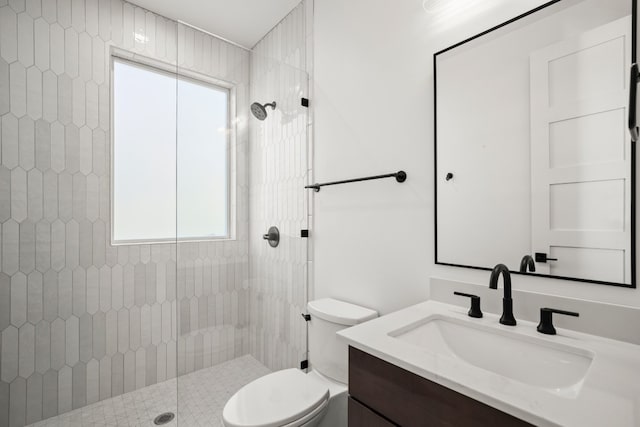 bathroom featuring toilet, a tile shower, and vanity