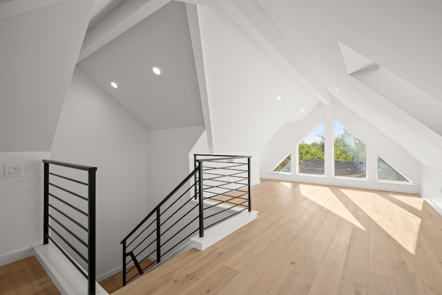 bonus room featuring light wood-type flooring and vaulted ceiling with beams