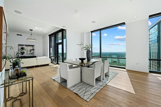 dining area with light hardwood / wood-style floors, a healthy amount of sunlight, and floor to ceiling windows