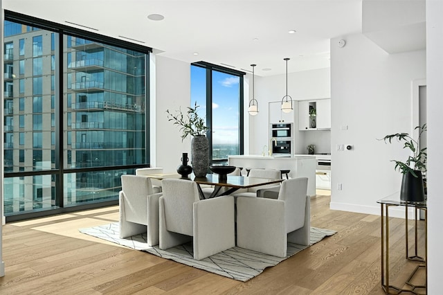 dining area with light hardwood / wood-style floors and a wall of windows