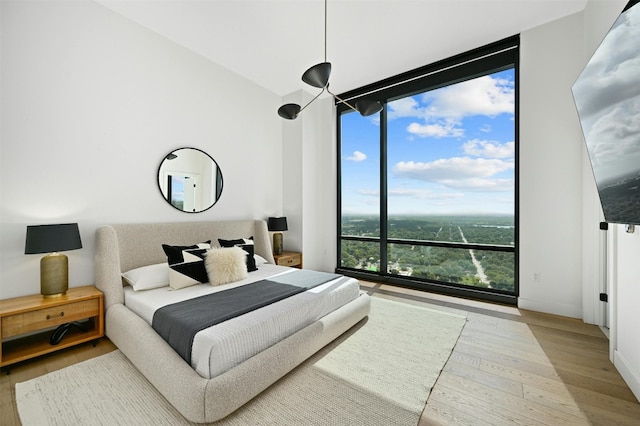 bedroom featuring wood-type flooring and a wall of windows