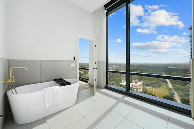 bathroom featuring tile patterned flooring, a wall of windows, and a tub