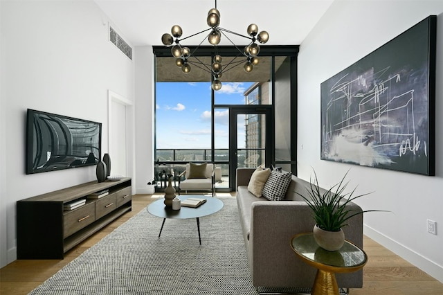 living room with hardwood / wood-style floors, a wall of windows, and a chandelier