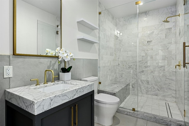 bathroom featuring vanity, a shower with door, toilet, and tile walls