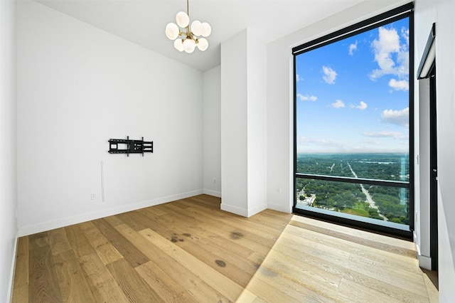 empty room with hardwood / wood-style flooring and an inviting chandelier