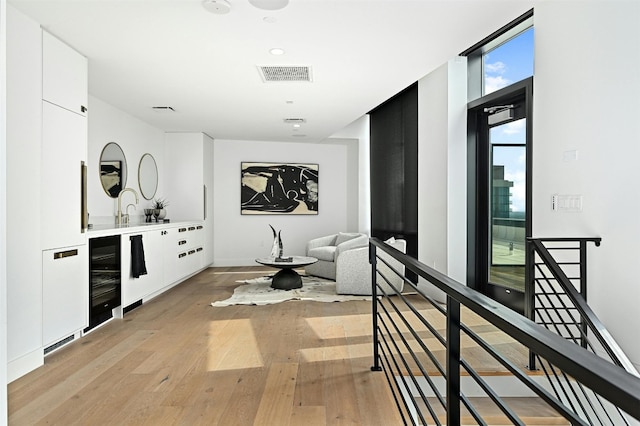 interior space with hardwood / wood-style floors, vanity, floor to ceiling windows, and wine cooler