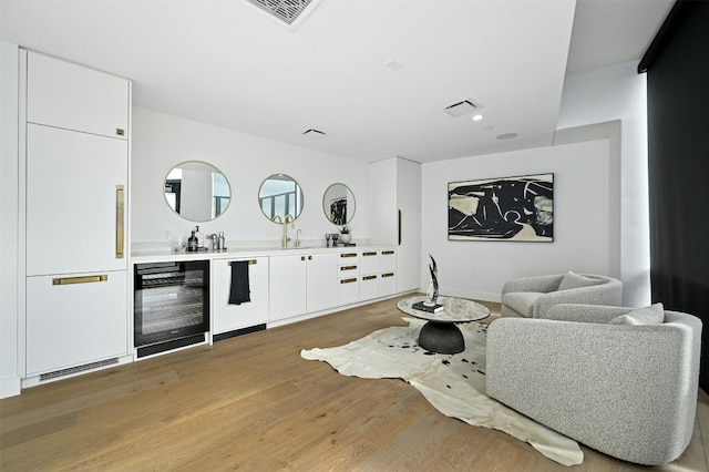 bar featuring white cabinets, dishwasher, light wood-type flooring, and beverage cooler