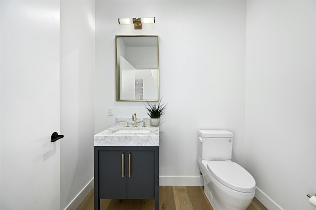 bathroom with wood-type flooring, vanity, and toilet