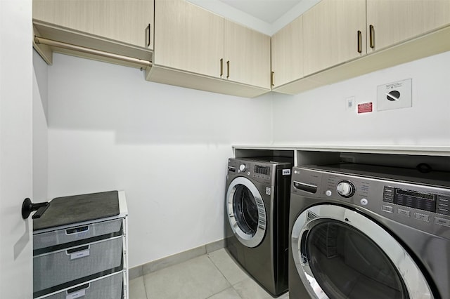 clothes washing area with light tile patterned flooring, cabinets, and independent washer and dryer