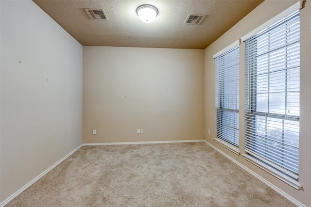 spare room featuring light carpet and a textured ceiling