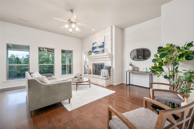 living room featuring ceiling fan, dark hardwood / wood-style floors, and a fireplace