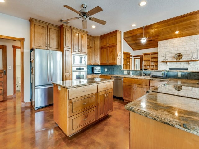 kitchen featuring a textured ceiling, stainless steel appliances, a kitchen island, ceiling fan, and concrete flooring