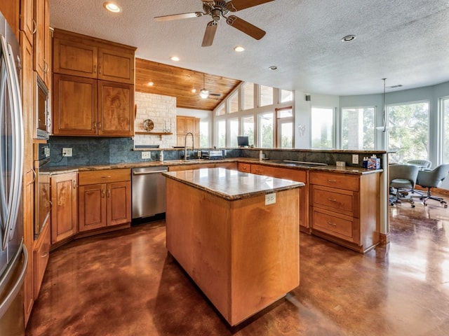 kitchen with a textured ceiling, a center island, stainless steel appliances, and ceiling fan