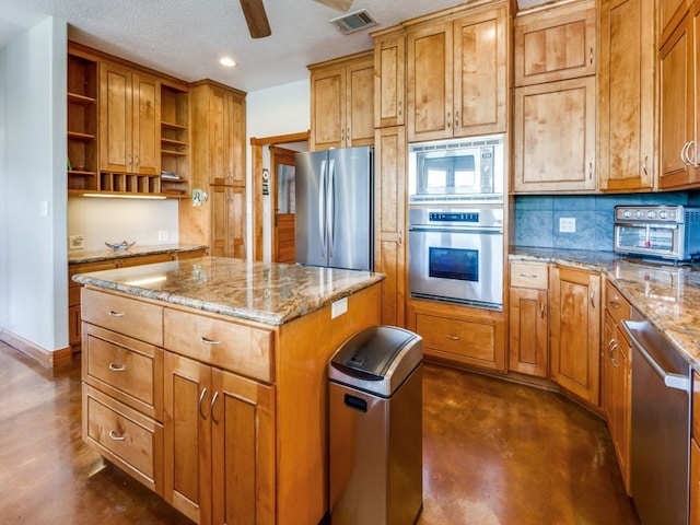 kitchen featuring a textured ceiling, light stone countertops, appliances with stainless steel finishes, a center island, and decorative backsplash