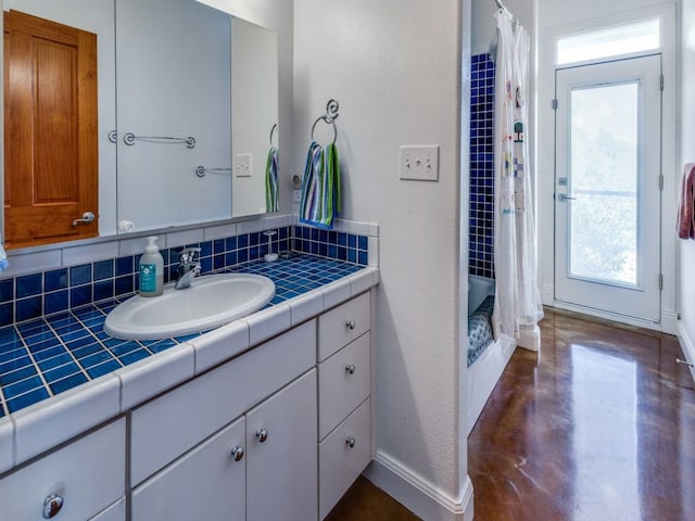 bathroom with concrete flooring, shower / bath combo with shower curtain, tasteful backsplash, and vanity