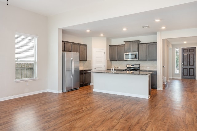 kitchen featuring dark stone countertops, a wealth of natural light, hardwood / wood-style floors, and stainless steel appliances