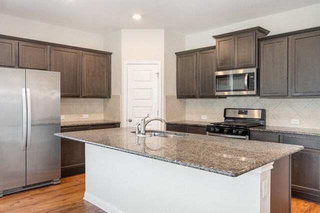 kitchen with stainless steel appliances, light hardwood / wood-style floors, a kitchen island with sink, and sink