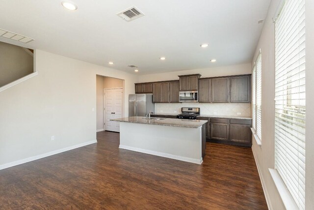 kitchen featuring backsplash, appliances with stainless steel finishes, sink, dark hardwood / wood-style floors, and a kitchen island with sink