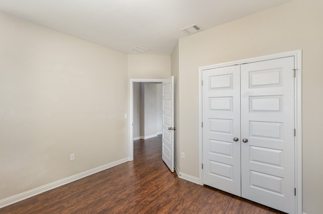 unfurnished bedroom with a closet and dark hardwood / wood-style flooring