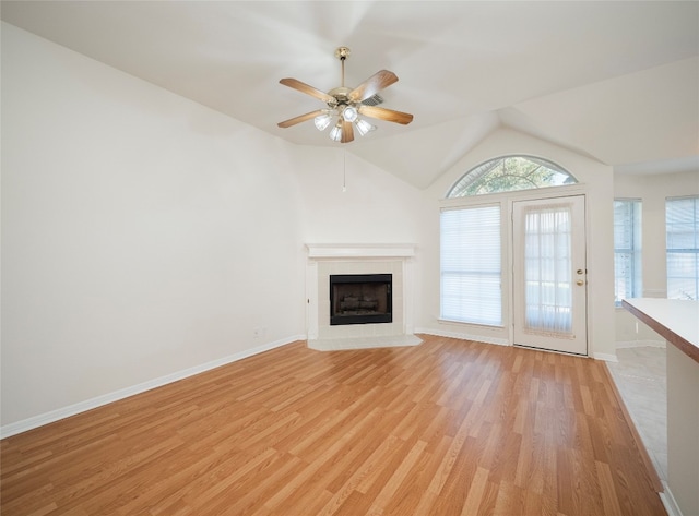 unfurnished living room featuring ceiling fan, light wood-type flooring, vaulted ceiling, and a fireplace