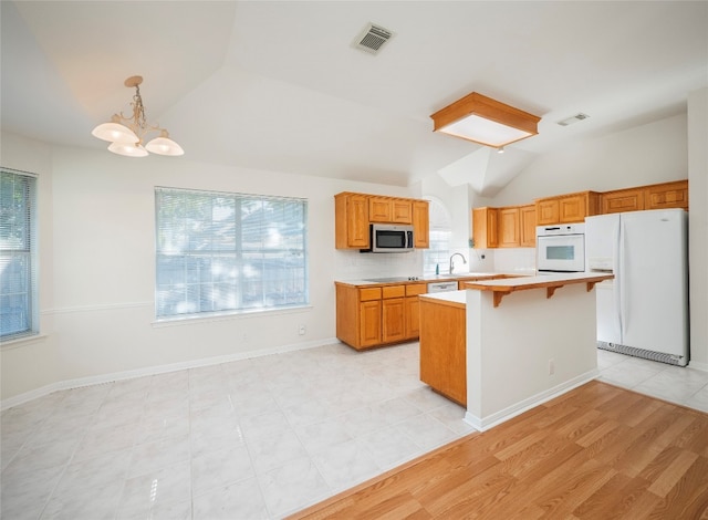 kitchen featuring a wealth of natural light, a breakfast bar, light hardwood / wood-style flooring, and white appliances