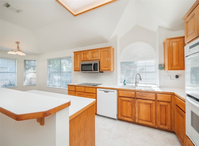 kitchen with vaulted ceiling, white appliances, backsplash, a breakfast bar, and sink