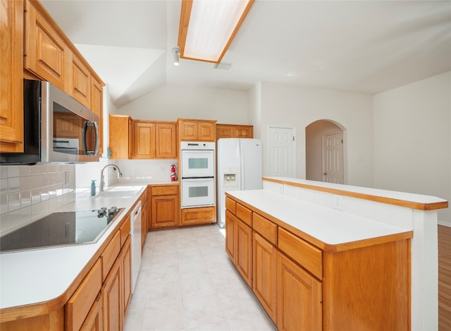 kitchen with white appliances, tasteful backsplash, light tile patterned floors, a center island, and sink