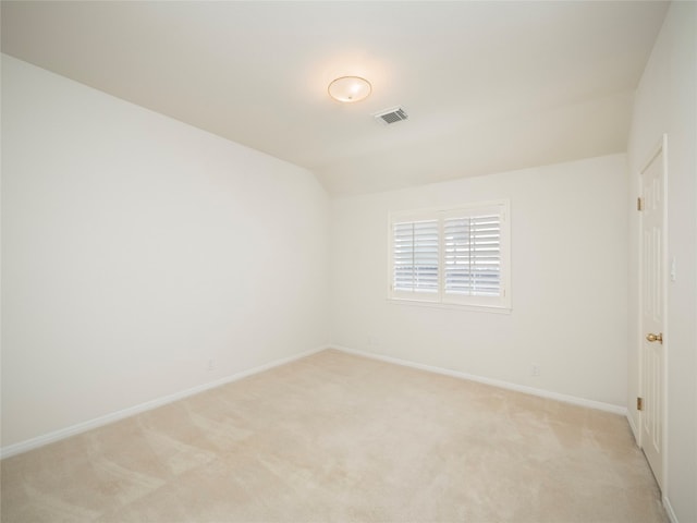 carpeted spare room featuring vaulted ceiling