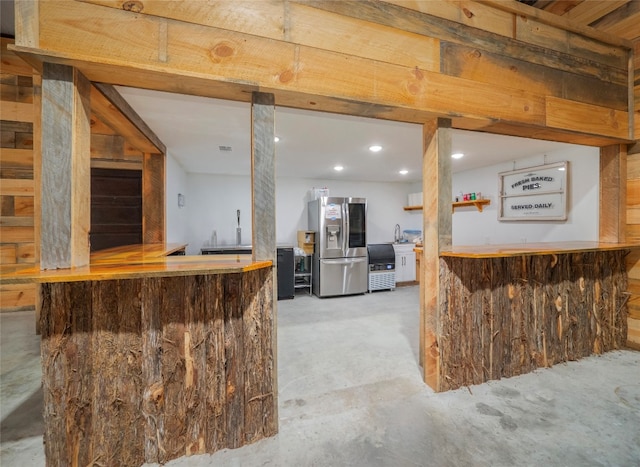 bar featuring stainless steel fridge with ice dispenser