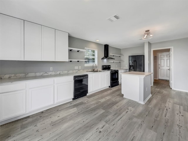 kitchen with light wood-type flooring, white cabinetry, sink, black appliances, and a kitchen island