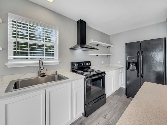 kitchen with black appliances, sink, wall chimney exhaust hood, white cabinets, and light hardwood / wood-style floors