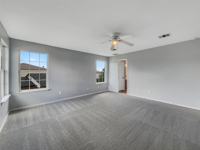 empty room with a wealth of natural light, ceiling fan, and carpet floors