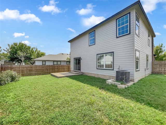 rear view of property featuring central air condition unit, a lawn, and a patio