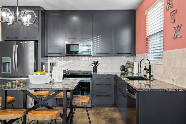 kitchen with pendant lighting, backsplash, sink, dark stone countertops, and appliances with stainless steel finishes