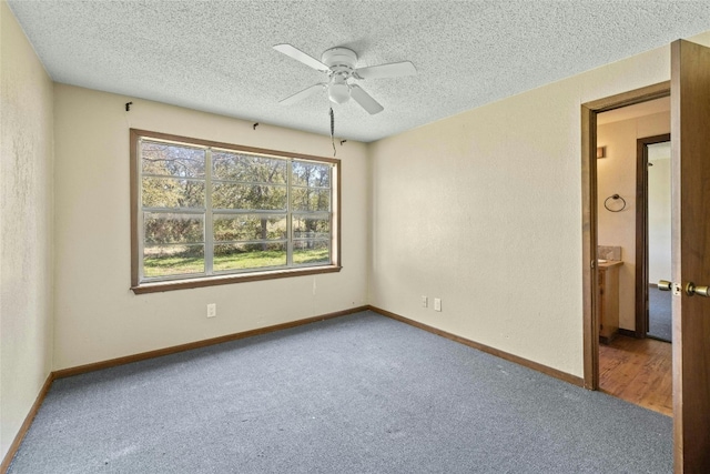 empty room with a textured ceiling, baseboards, and carpet floors