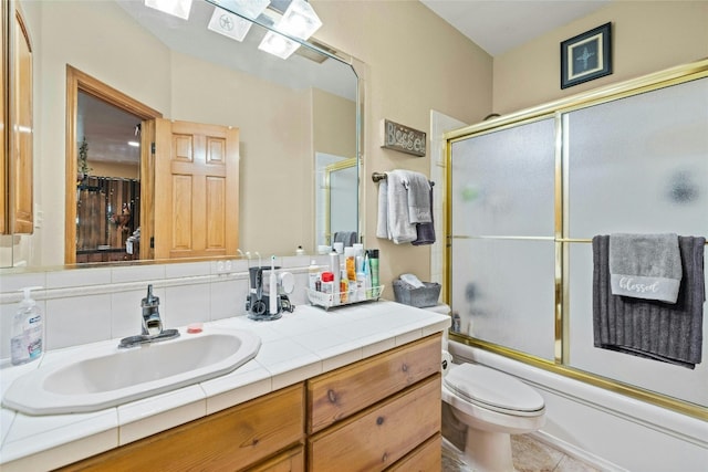 bathroom with tile patterned floors, toilet, vanity, and shower / bath combination with glass door