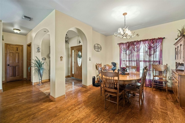 dining area featuring visible vents, baseboards, wood finished floors, arched walkways, and a notable chandelier