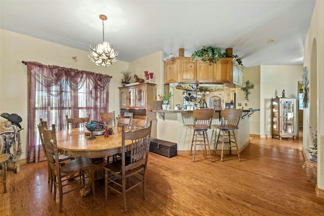 dining space featuring light wood-style floors, baseboards, and a chandelier