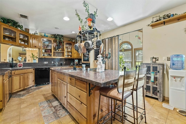 kitchen featuring visible vents, dishwasher, a kitchen bar, and a sink