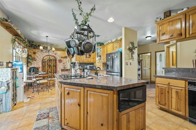 kitchen with light tile patterned floors, a center island with sink, stainless steel fridge with ice dispenser, a sink, and brown cabinets