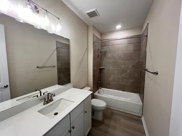 full bathroom with tiled shower / bath, vanity, toilet, and hardwood / wood-style floors